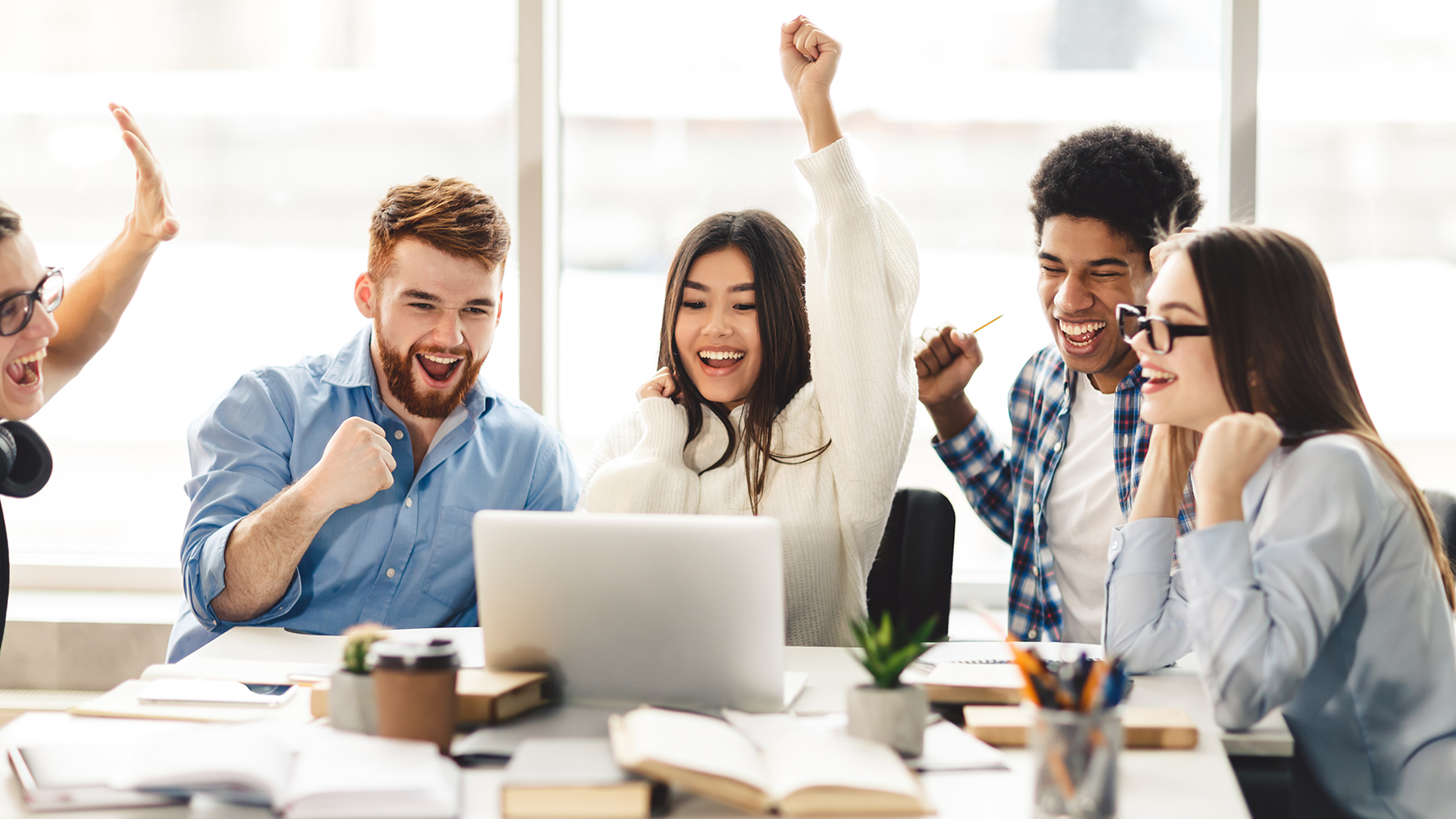 Students cheering while looking at a laptop