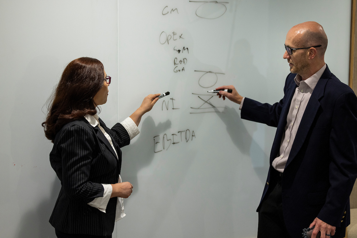two professionals looking at a whiteboard