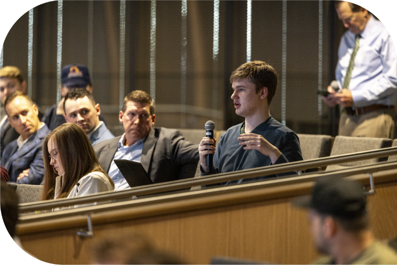 An audience member at a conference holding a mic to ask a speaker a question.