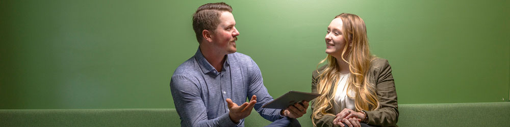A man and a woman talking to each other, while the man is holding an iPad.