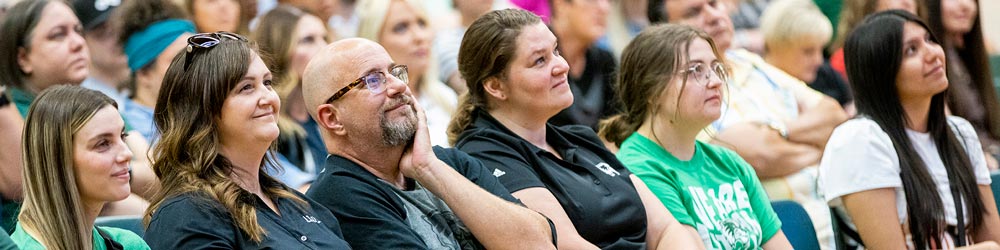 Parents and student sitting in an auditorium listening to someone speak.