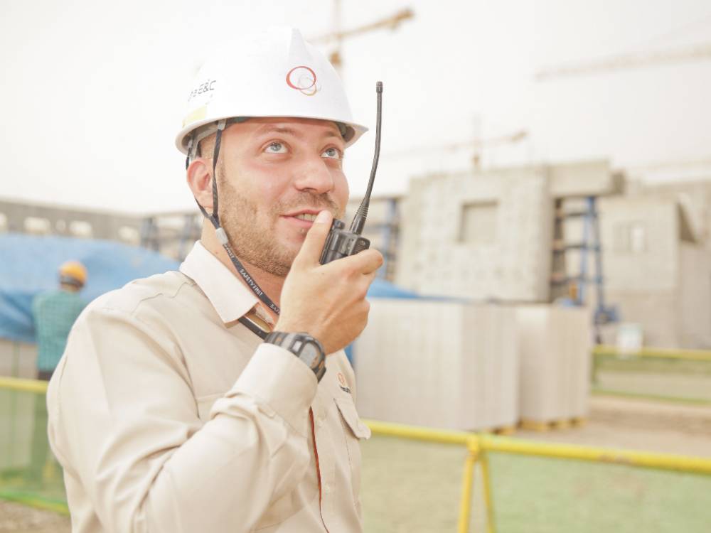 Man wearing a hardhat speaking into a walkie-talkie