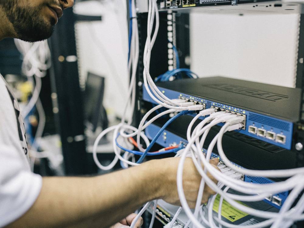 Man working with wires attached to a computer in a rack