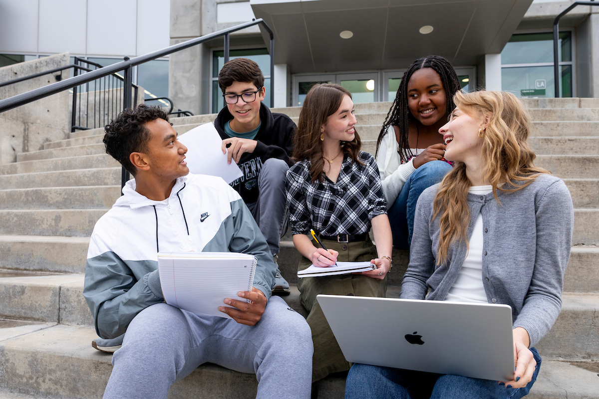 Students sitting together on steps with their laptops out