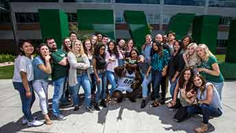 large group of students with school mascot in front of giant letters UVU