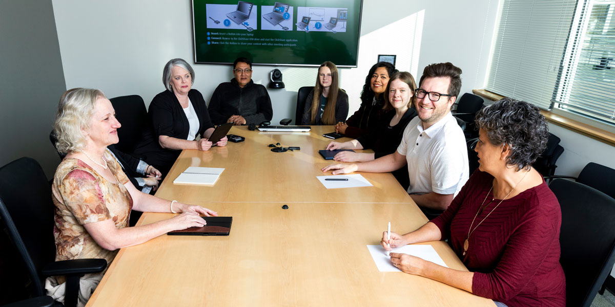Eight employees sitting around a conference table having a discussion.