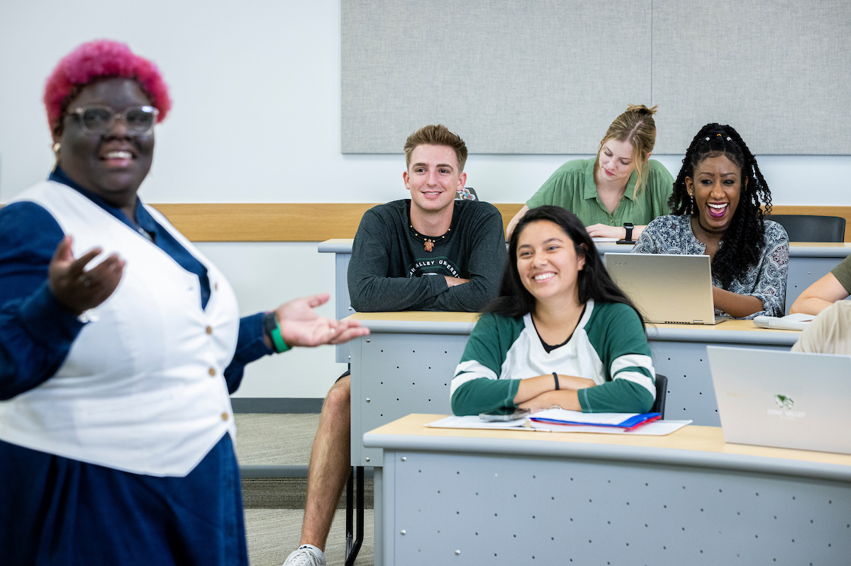 Group of students in an auditorium-style classroom with instructor teaching.