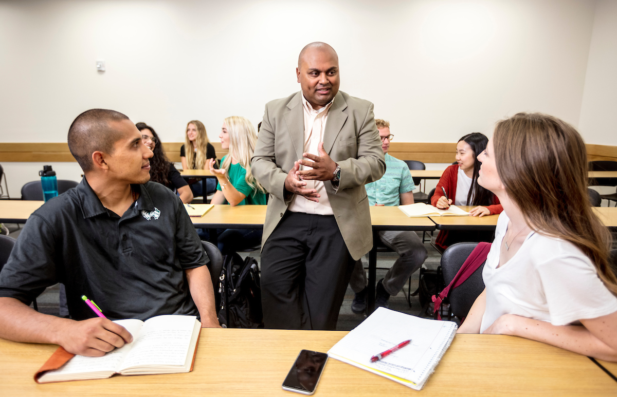 Students and faculty in discussion in a lecture hall.