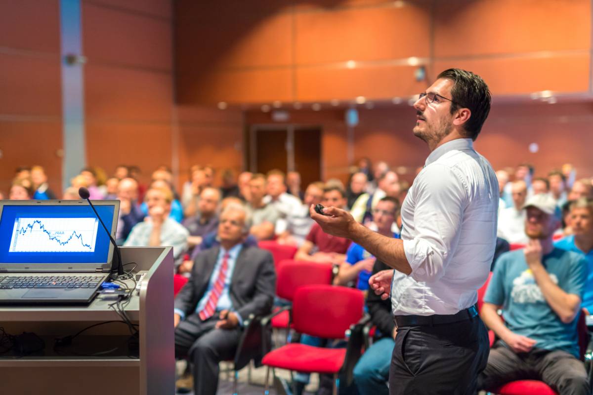 Man giving a presentation to a full auditorium of listeners