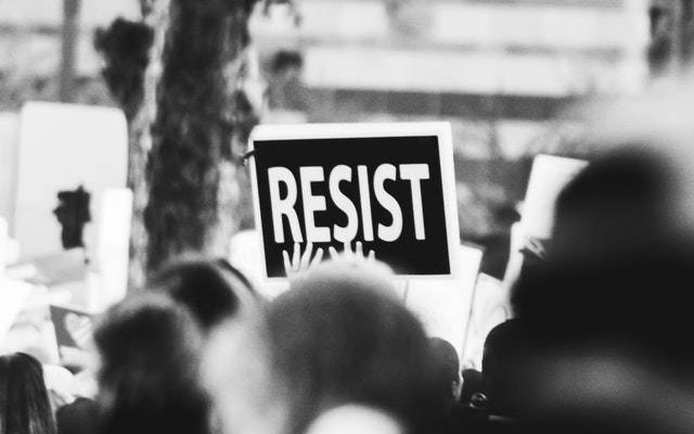 A sign held at a protest that says 'Resist'