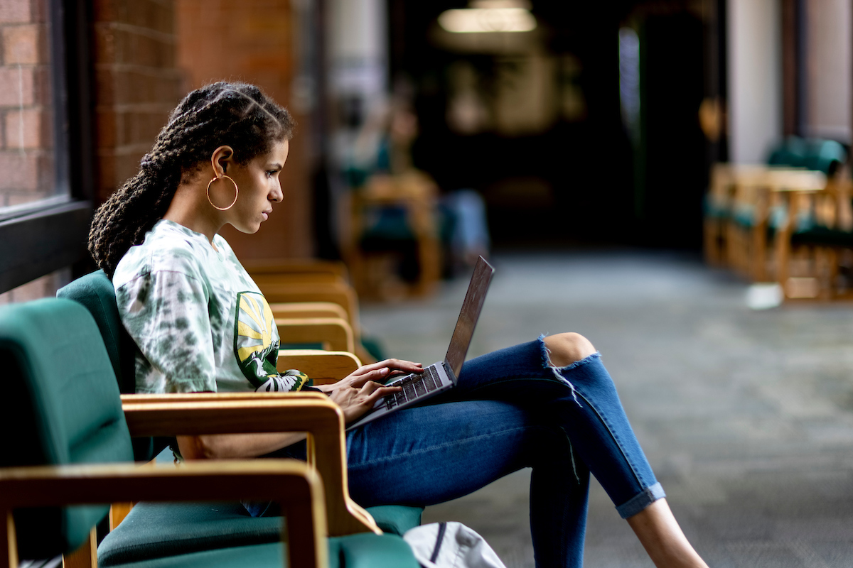 Image of a student looking at their laptop that is placed on their lap