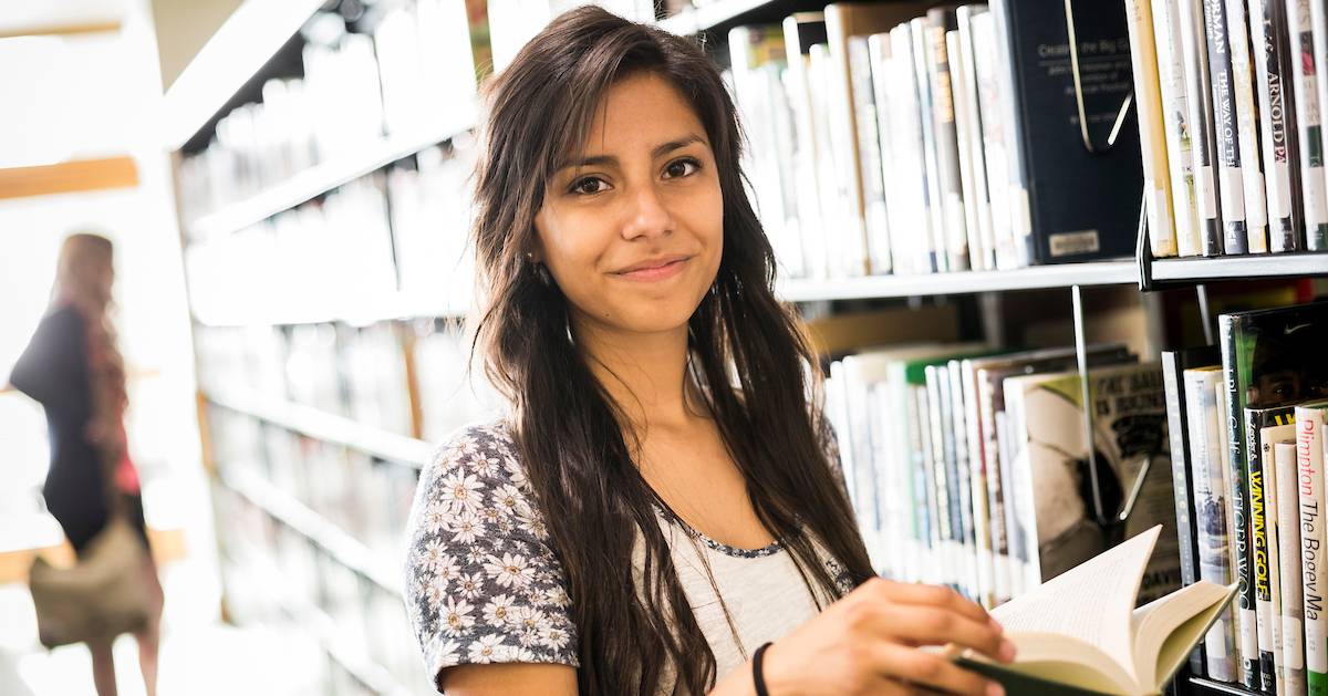 a student in the Fulton library holding a book