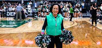 President Tuminez on a basketball court holding pom poms