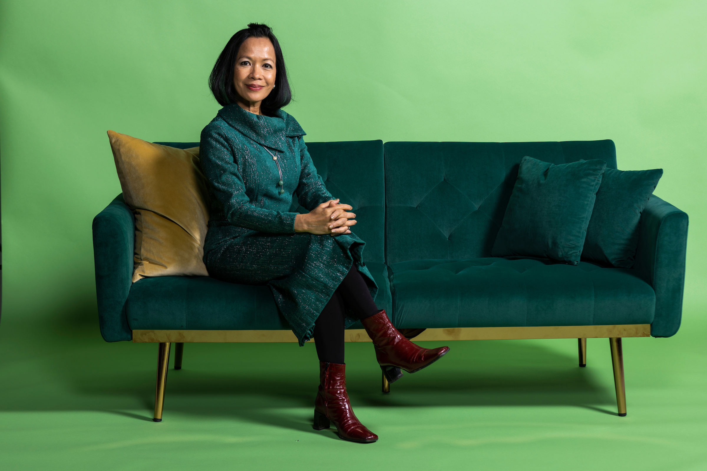 President Tuminez sitting on a couch with a happy expression on her face.