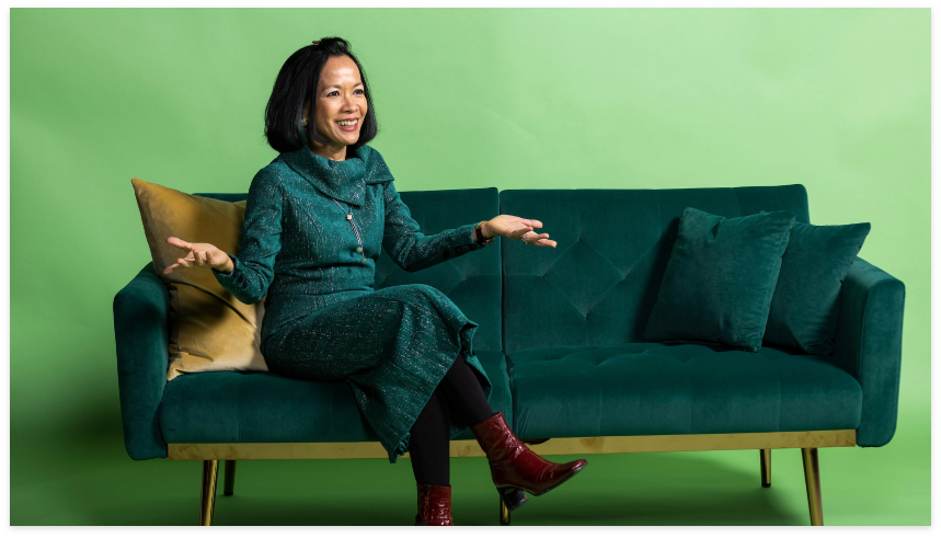President Tuminez sitting on a couch with a happy expression on her face.
