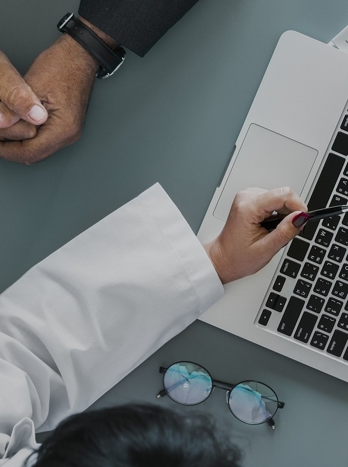 Person pointing to a computer in front of another person