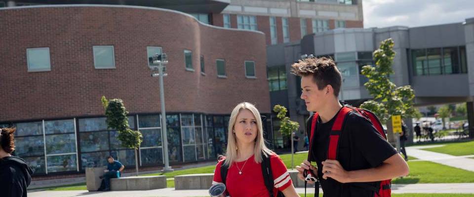 A woman and man walking outside talking to each other.