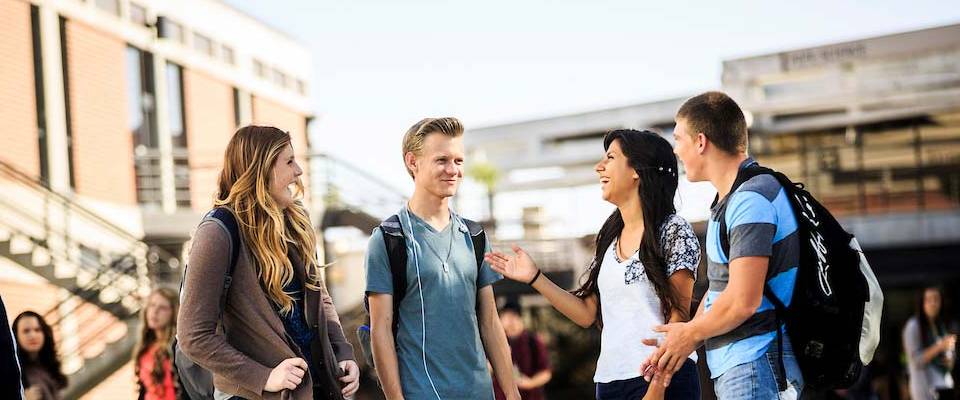 Four students standing outside talking to each other.