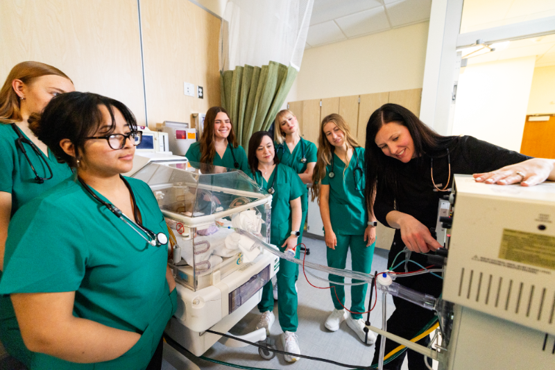 Instructor educating students on how to use an oscillator for neonatal patients. 
