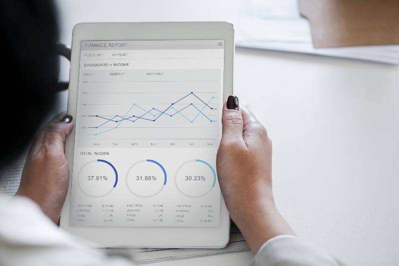 A woman looking at financial reports on a white tablet