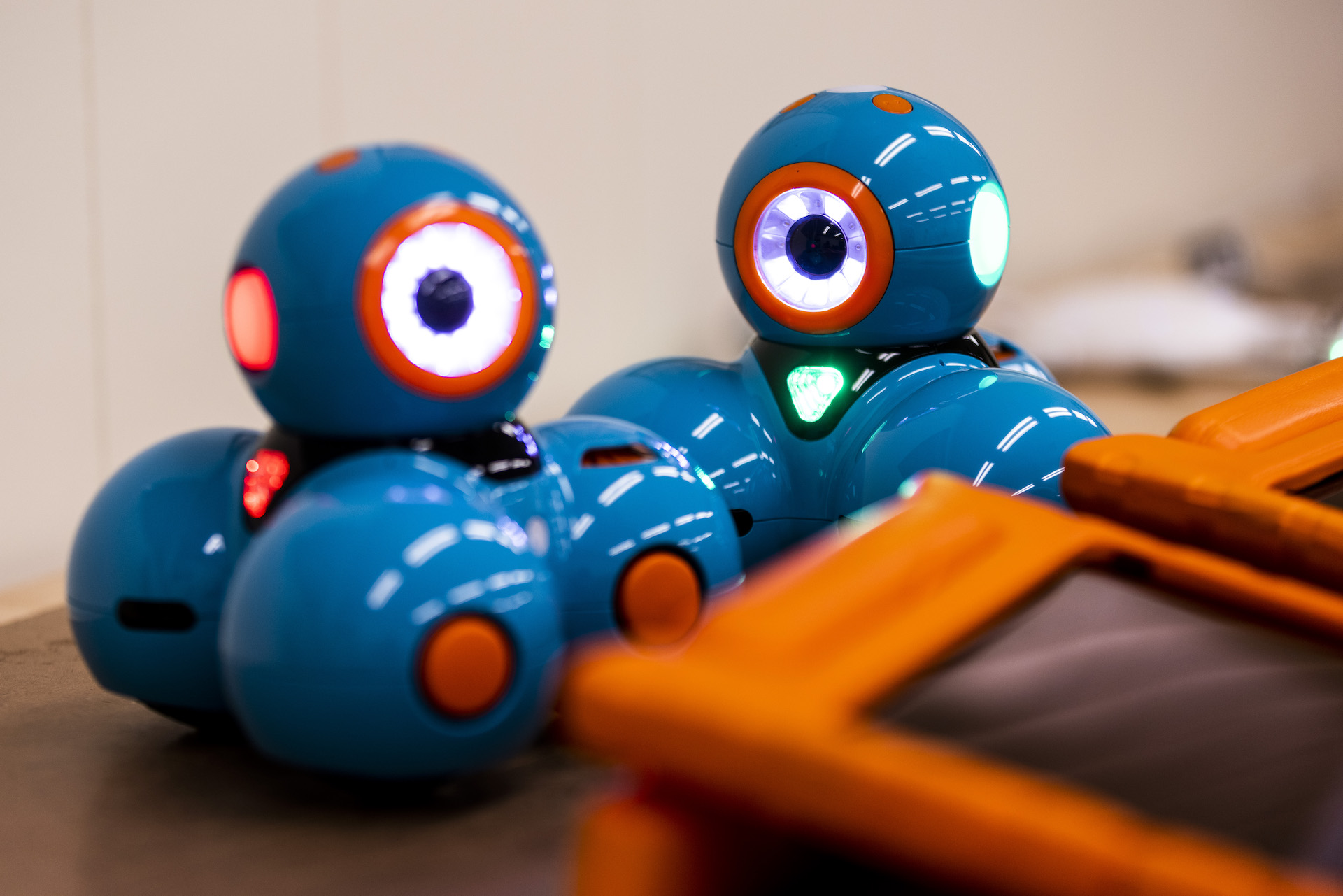 two Dash robots with their lights on