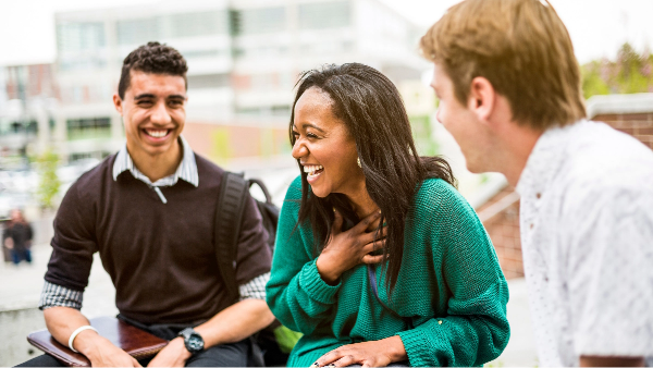 Three students sitting together and laughing.