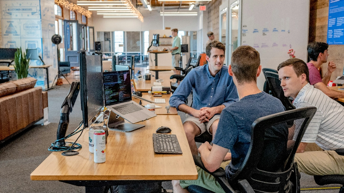 People in conversation at a desk.