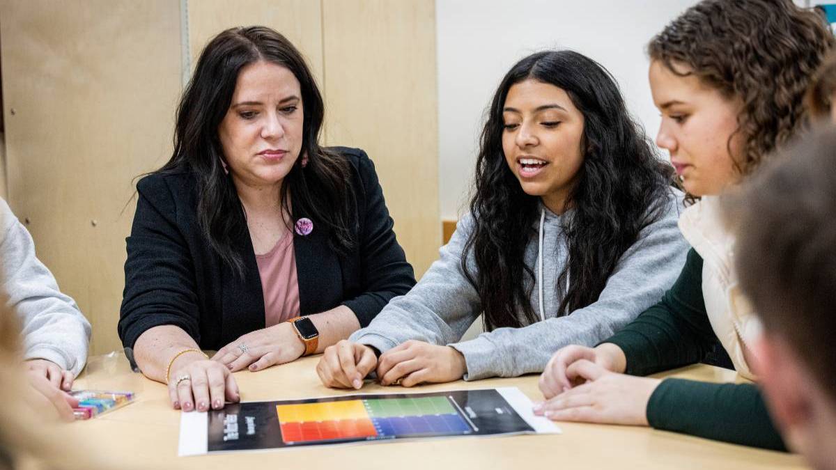 Teacher and students working at a table.