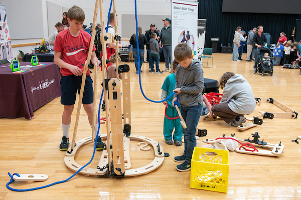 Multiple children working on large, wooden project in gymnasium