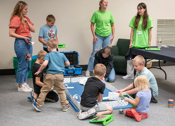 Various children playing while three adults watch over them