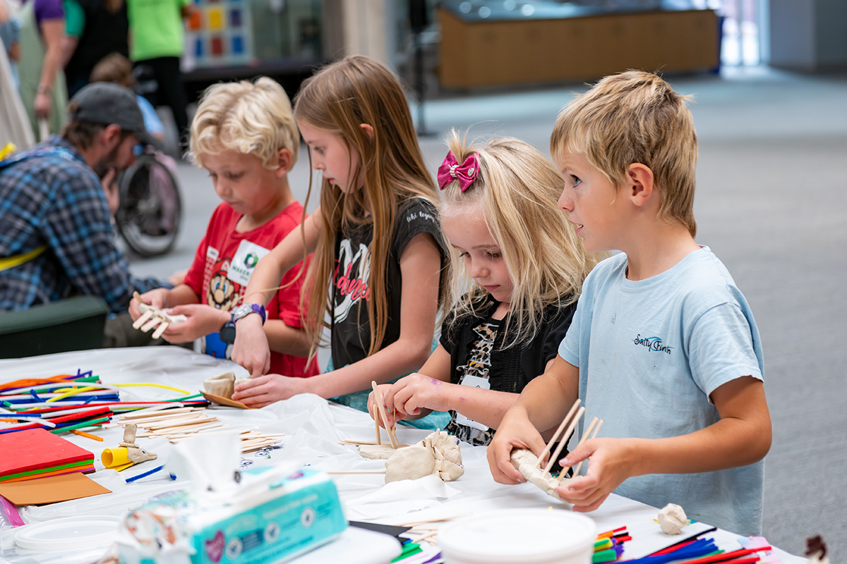Four children at a table working on art projects.