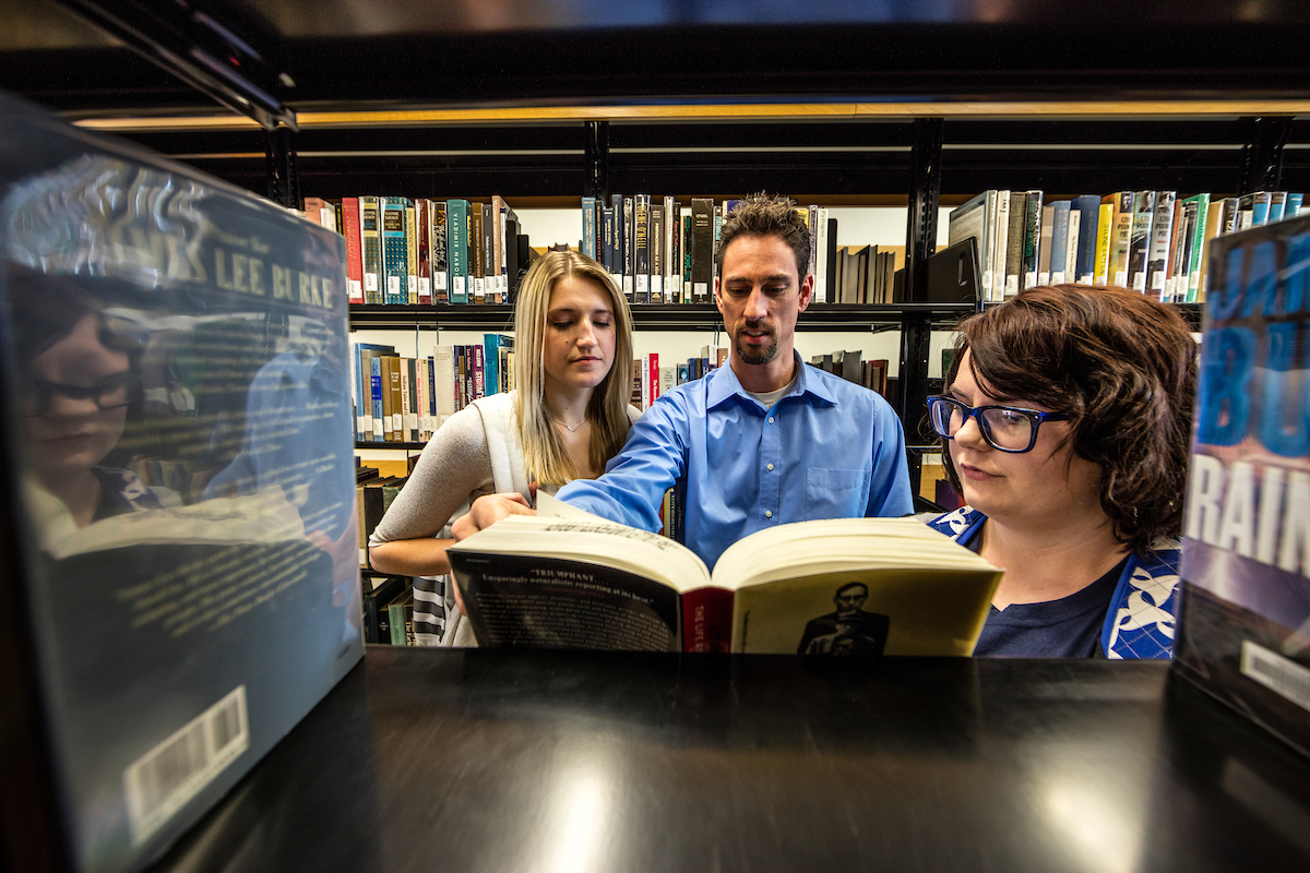 Students and their professor looking through books at the library