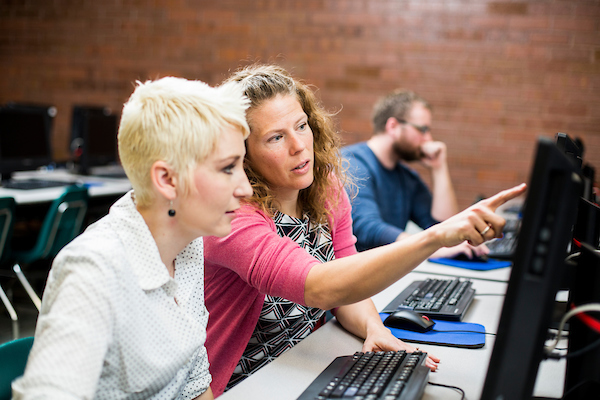 A teacher helping a student in a computer lab