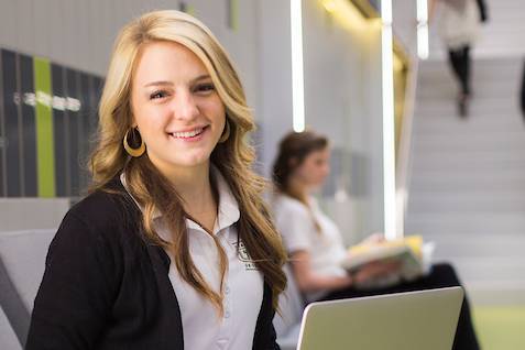 An employee holding a laptop in a hallway