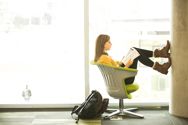 A student reading a book with feet propped up