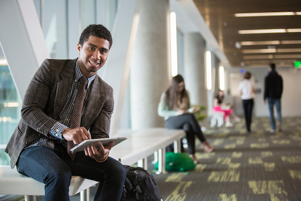 A student holding tablet in a hallway