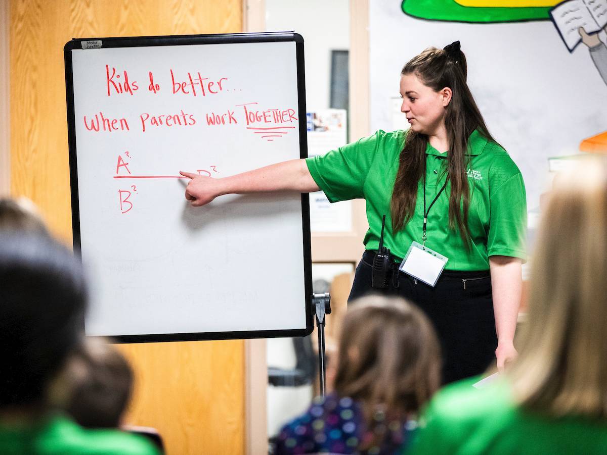 A coach points to the whiteboard with the message "kids do better when parents work together!"