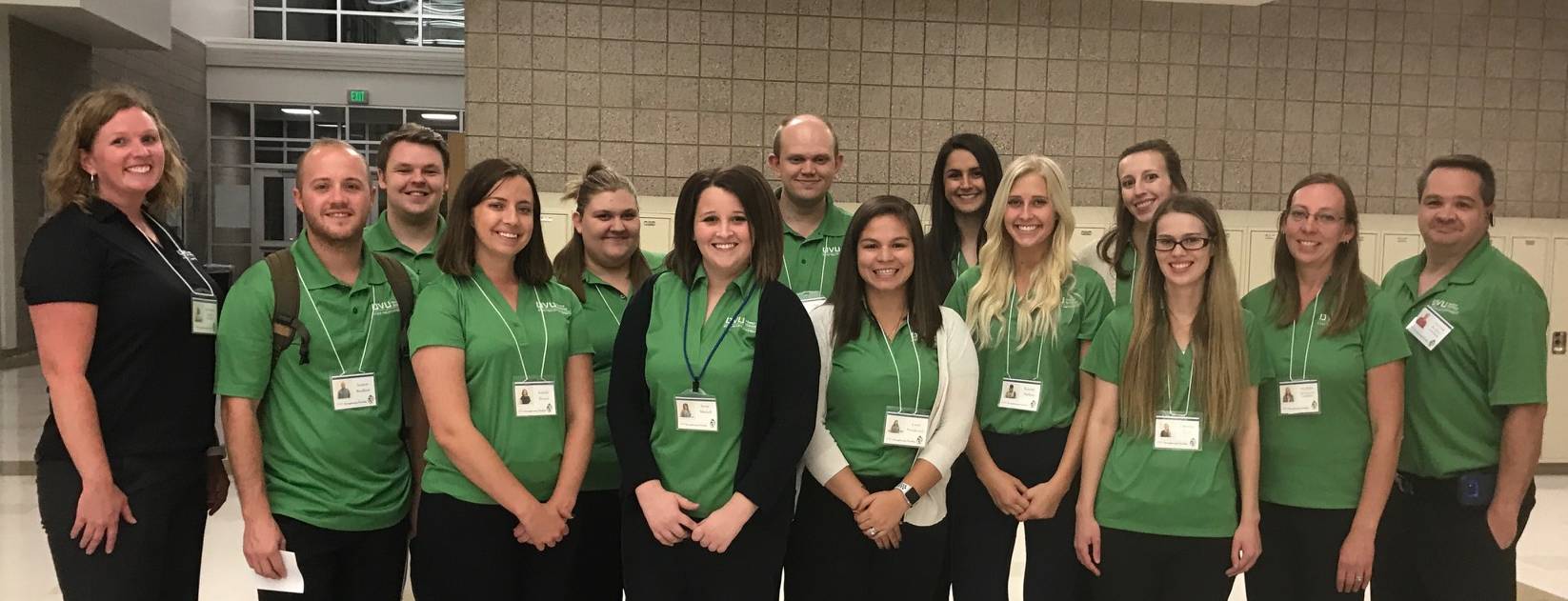 A group of interns in green shirts stand together, smiling