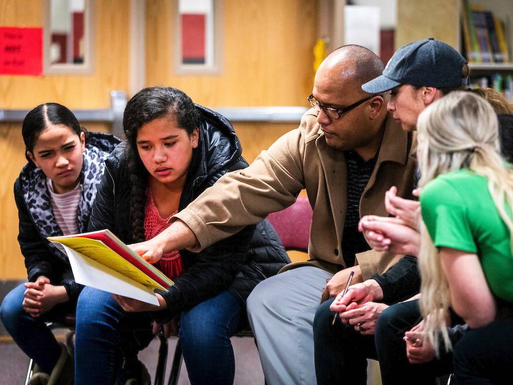 A father and two children look at the family workbook with their coach