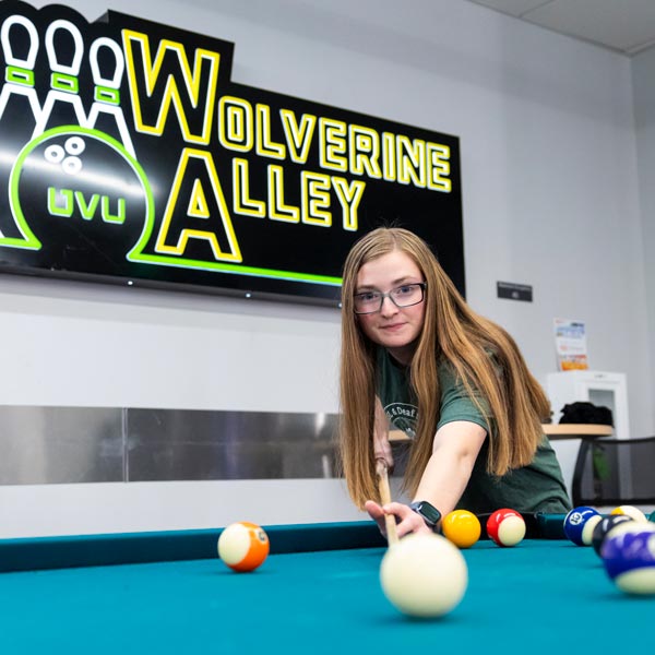 A student playing pool at the UVU gaming center