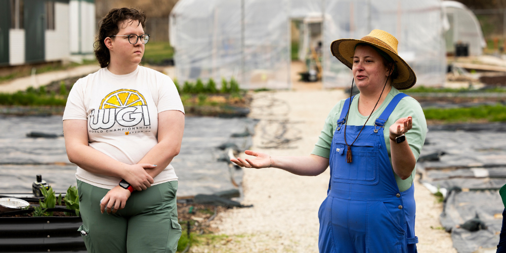 A pair of UVU's community social impact partners standing in front of the GRIT garden.
