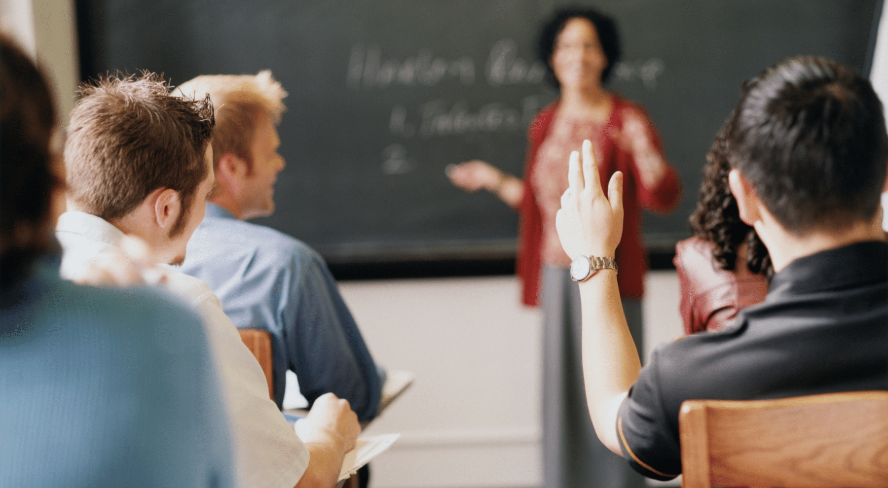 teacher at the chalkboard, student raising hand