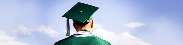 A graduating student wearing a green cap and gown.