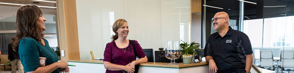 Three student success staff members talking in front of the reception desk.