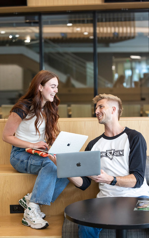 One student showing another student their laptop screen.