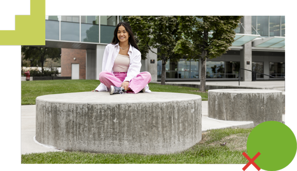 A smiling student sitting cross-legged outside of the Fulton Library.