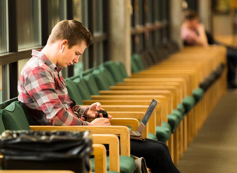 A man sitting looking at his laptop in the Hall of Flags.