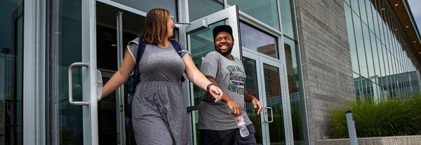 Two people exiting a building.