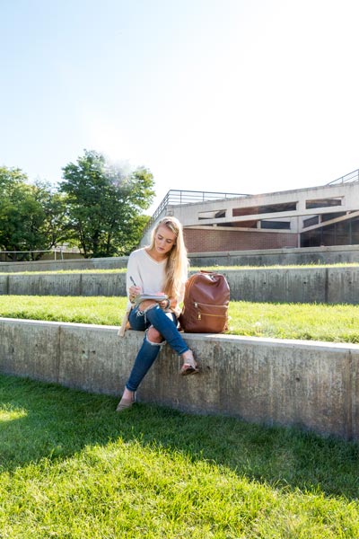 A woman sitting on a concrete ledge in a courtyard.