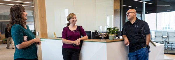 Three student success staff members talking in front of the reception desk.